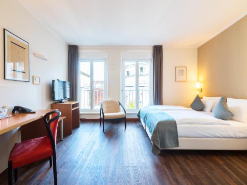 萨尔布吕肯雷汀格多米海景酒店的配有一张床和一张书桌的酒店客房