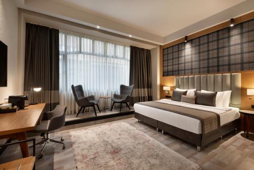 布达佩斯Ramada by Wyndham Budapest City Center的酒店客房,配有一张床、一张桌子和椅子