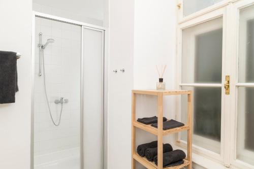 格拉茨The Ring Suites的带淋浴的浴室以及带毛巾的木制架子。