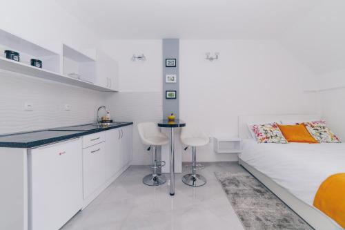 克拉古耶瓦茨Duga apartmani的白色的厨房配有2张凳子和1张床