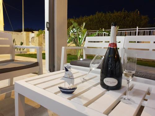 托雷拉皮罗La Baia Apartments的桌子上放有一瓶葡萄酒和两杯酒
