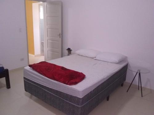 伊塔尼亚恩Apartamento à 50 metros da praia - Itanhaém的一间卧室配有一张床铺,床上铺有红色毯子