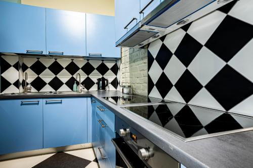 里加Blue Bird Hostel in Riga Old Town的厨房配有蓝色橱柜和黑白瓷砖