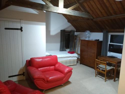锡廷伯恩Watercress Barns的一间带红色椅子的客厅和一间卧室