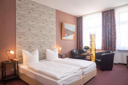 莱比锡亚达吉奥酒店的酒店客房带一张大床和两张椅子