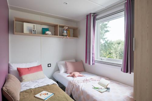 托尔雷莱Mobil Home XXL 4 chambres - Camping Les Tropiques的小房间设有床和窗户