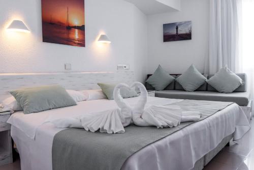 拉萨维纳Hostal Bellavista Formentera的两个白天鹅坐在一个房间里的床边