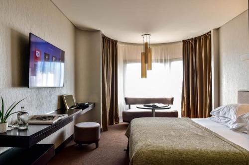 波尔图Porto Palácio Hotel by The Editory的配有一张床和一张书桌的酒店客房