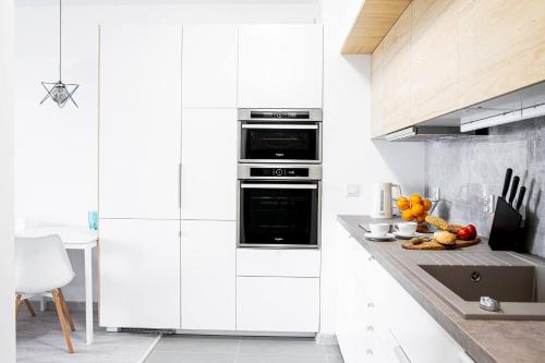 罗兹Apartments Drewnowska 43的白色的厨房配有白色橱柜和水槽