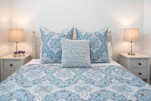 怀蒂昂格Beach Folly - Whitianga的一张带蓝色和白色枕头的床和两盏灯