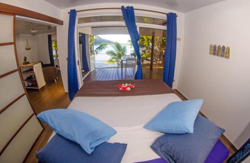 OpoaLe Neliza Beach Lodge Raiatea的一间卧室配有一张带蓝色枕头的床和一扇窗户。
