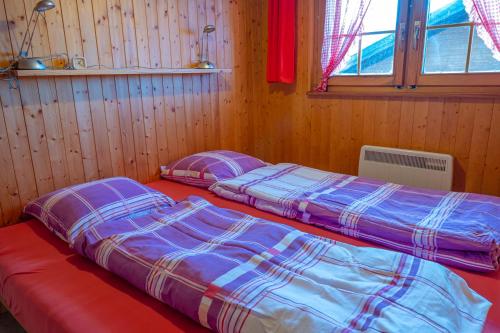 RosswaldChalet Allegra的木墙客房的两张床