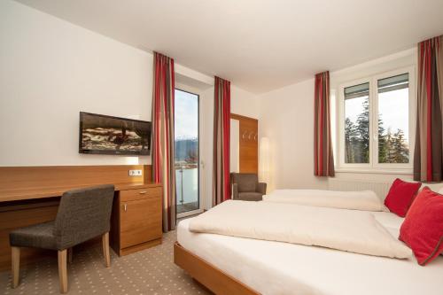 因斯布鲁克Seehof Innsbruck的酒店客房设有两张床、一张桌子和一台电视。