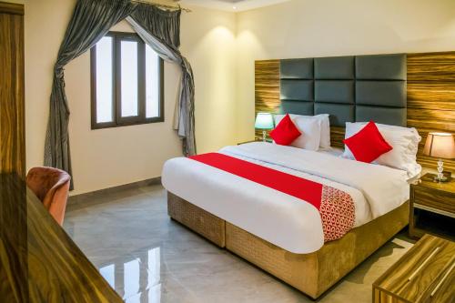 达曼Durra Taraf Residential 2的一间卧室配有一张带红色枕头的大床