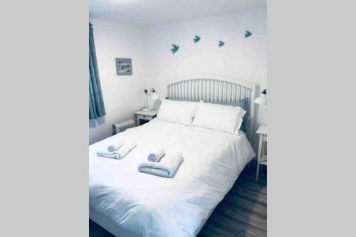 戈尔韦Fuchsia Apartment Tranquil Modern Seaside Apartment on the Wild Atlantic Way的卧室配有白色的床和2条毛巾