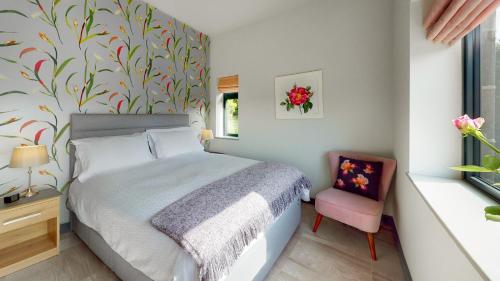 WortleyFinkle Green B & B的一间卧室配有一张床和一张粉红色的椅子