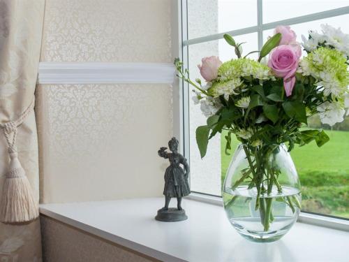 朗塞斯顿普尔农家乐的花瓶装满鲜花,坐在窗台上