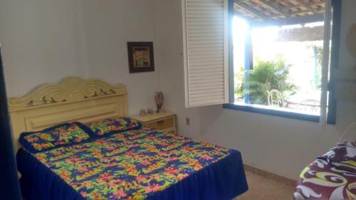 卡波布里奥Casa em Cabo Frio的一间卧室配有一张带彩色毯子和窗户的床。