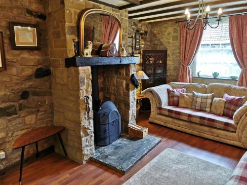 HighamPathways Cottage的客厅设有石制壁炉和沙发。