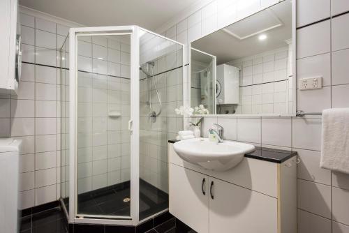 达尔文Darwin Executive Studio的白色的浴室设有水槽和淋浴。