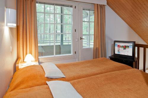 卡拉约基Holiday Club Kalajoki Cottages的一间卧室设有一张大型橙色床和一扇窗户。