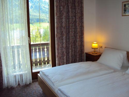魏森湖Haus Alpenfriede的一间卧室设有一张床和一个阳台的窗户。