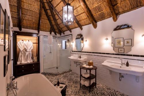 帕特森Lalibela Game Reserve - Kichaka Lodge的浴室配有2个盥洗盆、浴缸和淋浴。