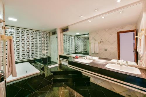 戈亚尼亚Plaza Inn Augustus的浴室配有2个盥洗盆、浴缸和镜子