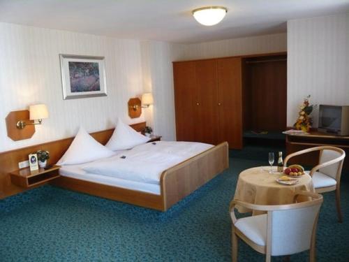 霍夫施特劳斯酒店的酒店客房设有一张大床和一张桌子。