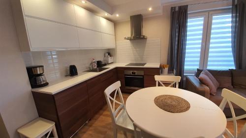 尤斯托尼莫斯基Apartamenty Waterline Ustronie Morskie的厨房以及带白色桌椅的起居室。