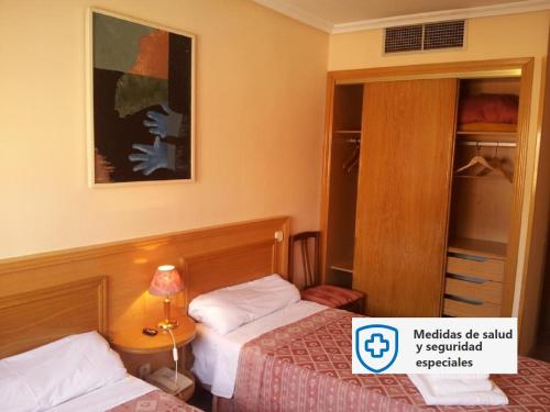 圣塞巴斯蒂安德洛斯雷耶斯若望二十三世旅馆的酒店客房,设有两张床和镜子