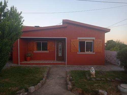 米纳斯Hosteling Las Margaritas的一座红色的房子,前门和院子