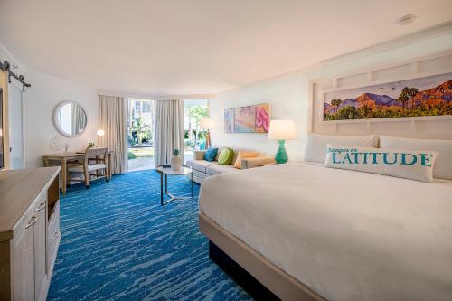棕榈泉Margaritaville Resort Palm Springs的酒店客房设有一张大床和一张书桌。