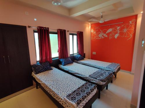 马尔万Bandekar Home Stay的宿舍间的两张床,设有红色的墙壁和窗户