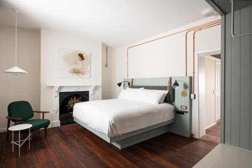 弗里曼特Warders Hotel Fremantle Markets的一间卧室配有一张床、一把椅子和一个壁炉