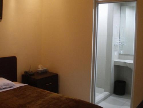 泗水Soerabaja Place Guest House的一间卧室设有淋浴、一张床和一个水槽。