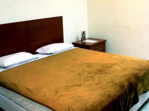 泗水Soerabaja Place Guest House的一间卧室配有一张大床和一个床头柜