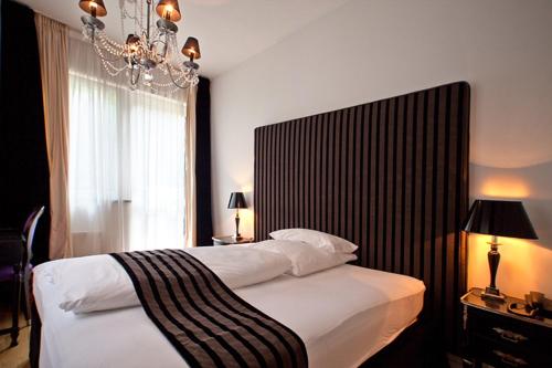 杜塞尔多夫亚历山大酒店的一间卧室配有一张大床和一个吊灯。