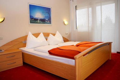 韦尔特湖畔克伦彭多夫胡蒂里斯特酒店的卧室配有带白色枕头的大型木质床。