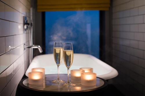 埃文河畔斯特拉特福杜文斯特拉特福德酒店的浴缸旁的托盘上放上两杯香槟酒和蜡烛