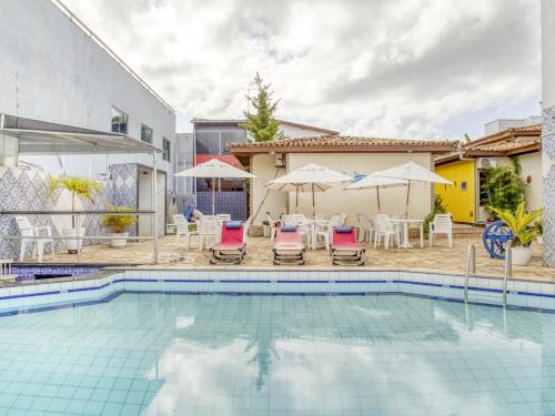 萨尔瓦多OYO Hotel Stella Maris - Salvador的房屋旁的游泳池配有椅子和遮阳伞