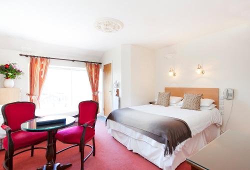 都柏林利森桥酒店的酒店客房,配有一张床和两张红色椅子