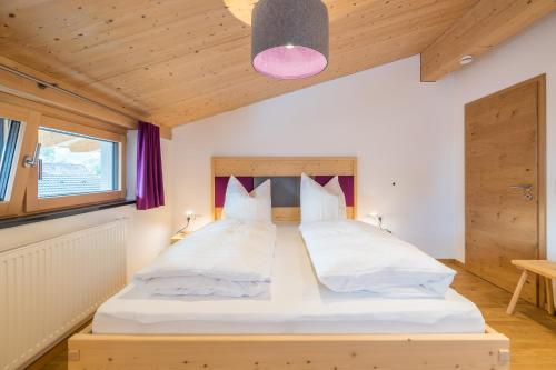 松托芬Stadt Chalet的卧室配有一张白色大床和木制床头板