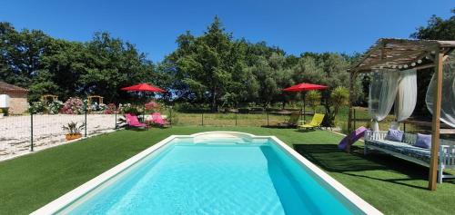 锡富尔勒普拉日Au Charme de Pépiole的庭院内的游泳池,配有椅子和遮阳伞