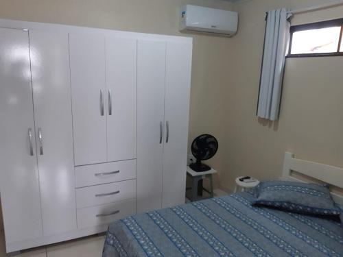 弗洛里亚诺波利斯Pousada Residencial Caroa的一间卧室配有一张床、白色橱柜和窗户。