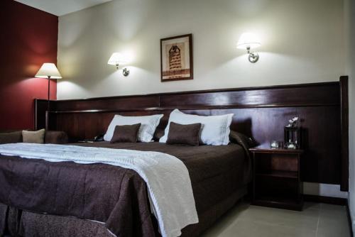 圣地亚哥-德尔埃斯特罗Hotel Ciudad的一间卧室配有一张大床和木制床头板