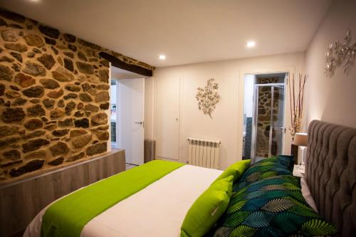 索尔波Apartamentos Casa dos Arcos的一间卧室配有一张带绿色枕头的床和石墙