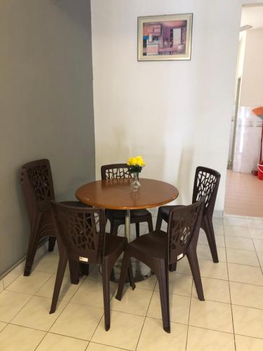 彭亨Bentong Makmur Guesthouse的一张木桌和椅子,上面有花瓶