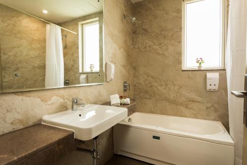古尔冈SILVER OAK near Medanta Medicity的一间带水槽、浴缸和镜子的浴室