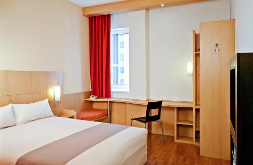 马里尼亚讷马赛普罗旺斯机场宜必思酒店的一间卧室配有一张床、一张书桌和一个窗户。